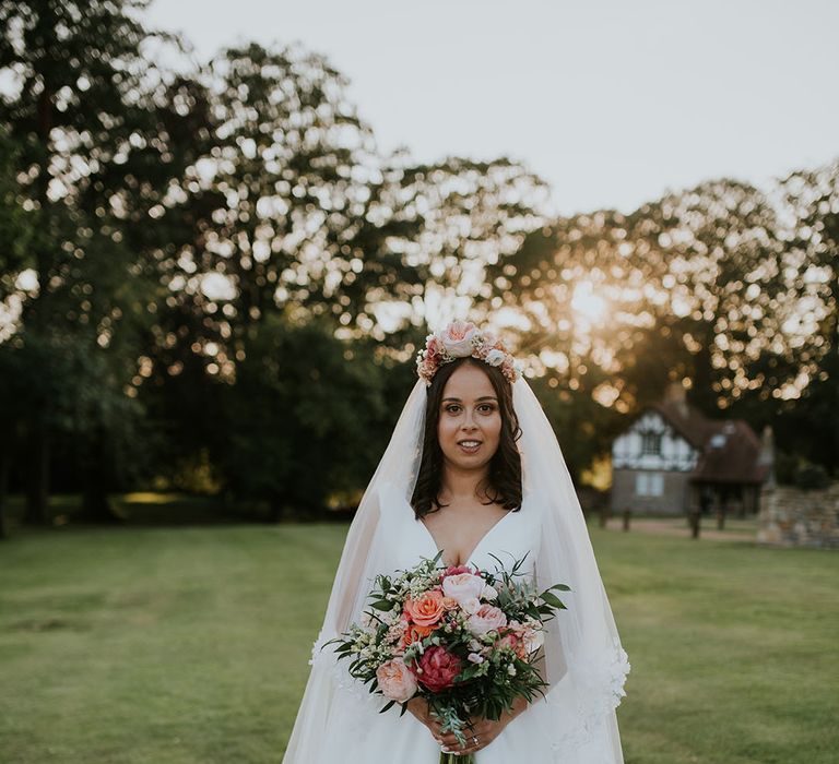 Stunning bride in v-neck Stella York wedding dress with bright and colourful bouquet for summer wedding with matching flower crown 