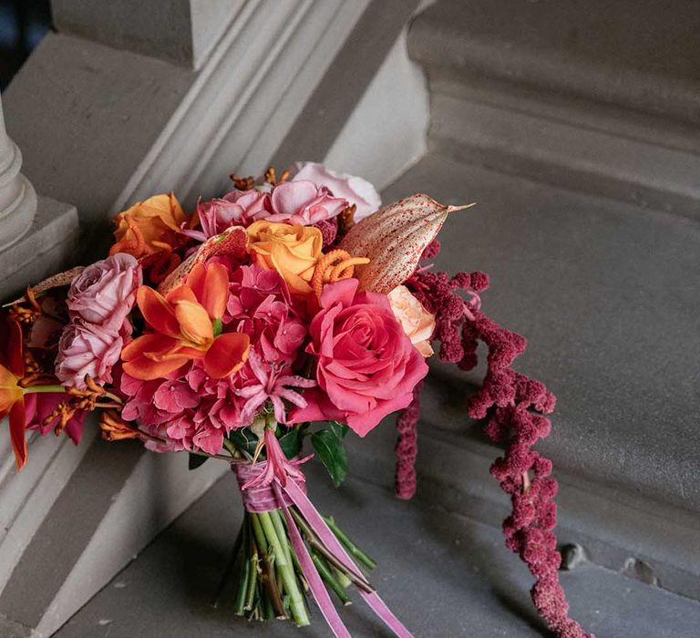 Bright tropical floral bouquet complete with roses and tied with pink ribbon 