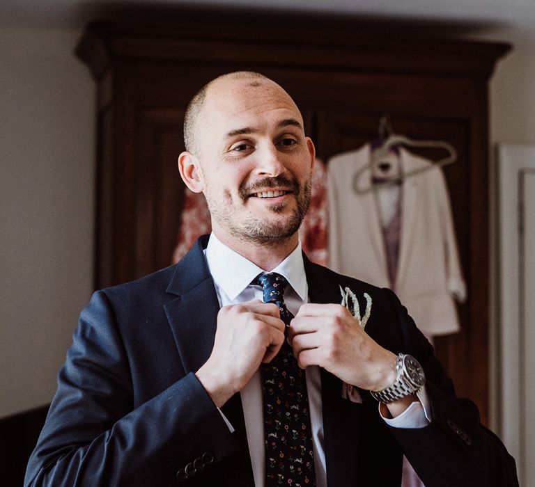 Groom in navy suit with an easter bunny tie and silver watch