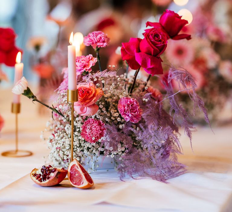 Bright pink floral centrepiece and dried fruit decor for modern tablescape 