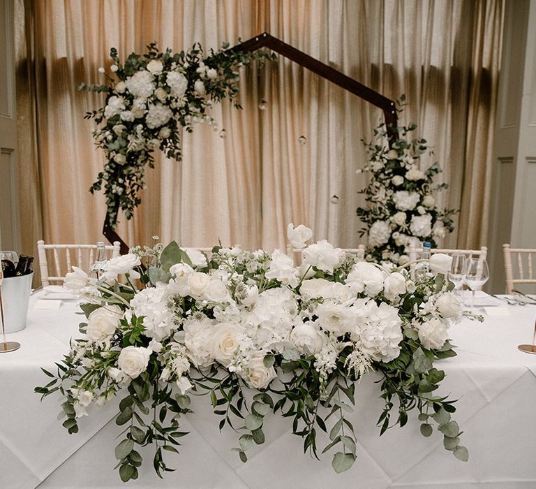 Hexagon wedding arch complete with white flowers and green foliage 