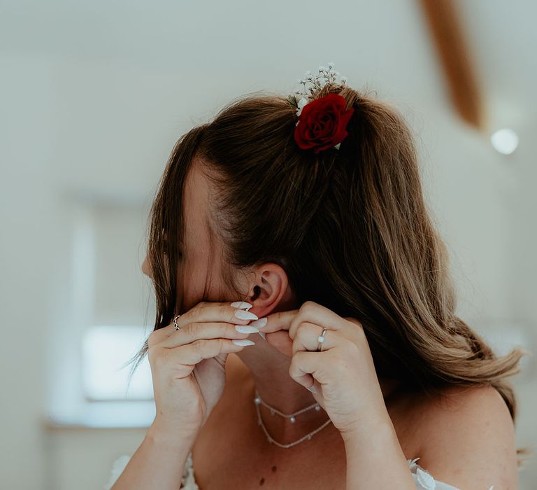 Bride with pointed stiletto nails puts in her earrings as she gets ready for her wedding day 