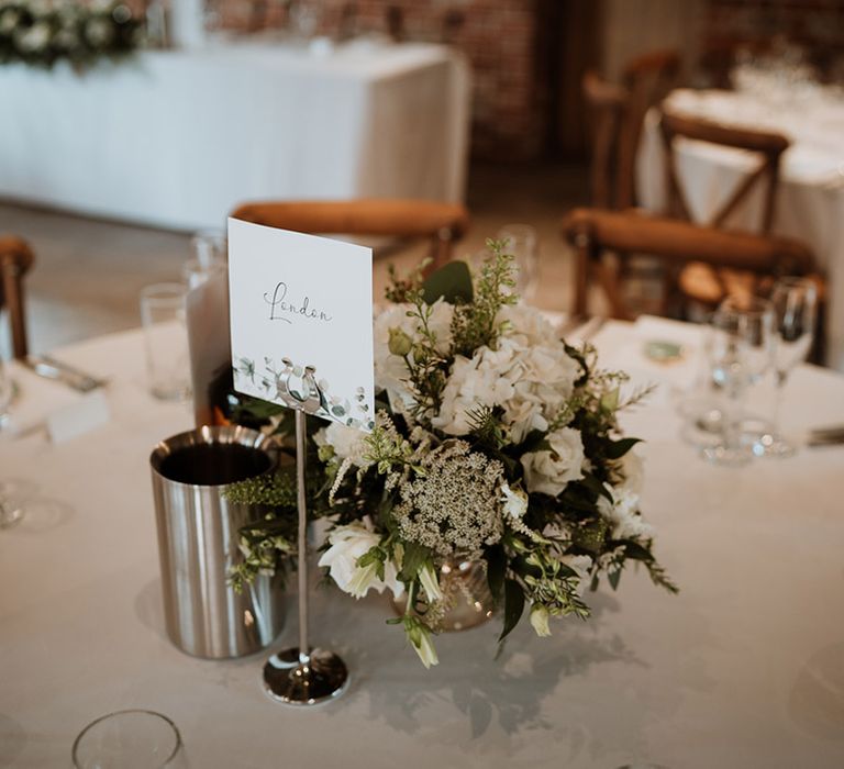 White card table name with foliage design with simple white flower centrepiece 