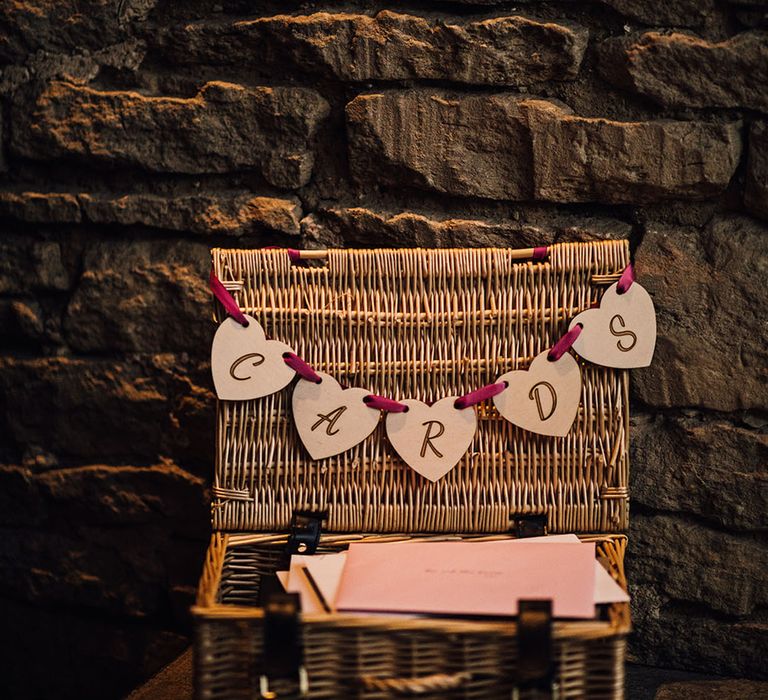 A wicker box with bunting lays on a table for the wedding cards 