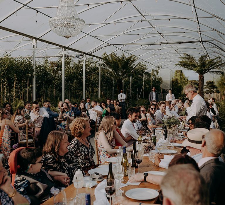 Seated guests in a greenhouse watching the speeches