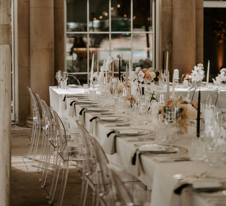 Neutral, pale pink, and black wedding tablescape with taper candles, roses, and orchids decorating the tables