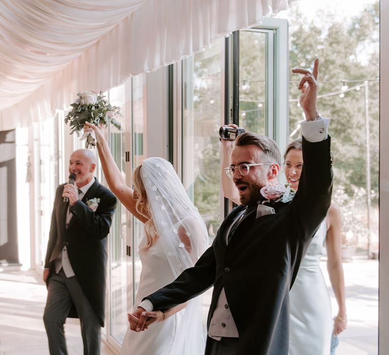 Bride and groom enter their wedding reception with flower applique veil