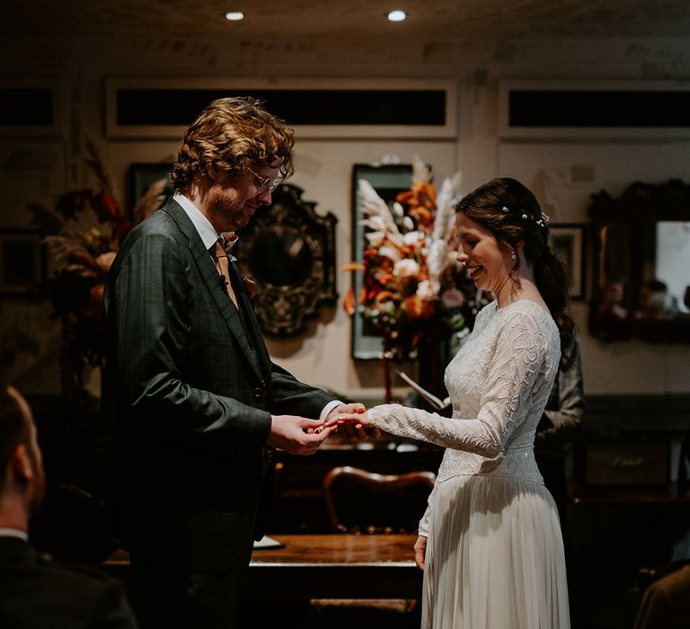 Bride and groom exchanging rings at autumnal London intimate wedding ceremony 