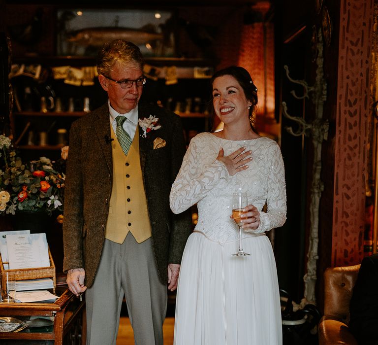 Bride in long vintage lace wedding dress with pearl necklace and pearl hair clips holding glass of champagne doing wedding speech at The Zetter Townhouse