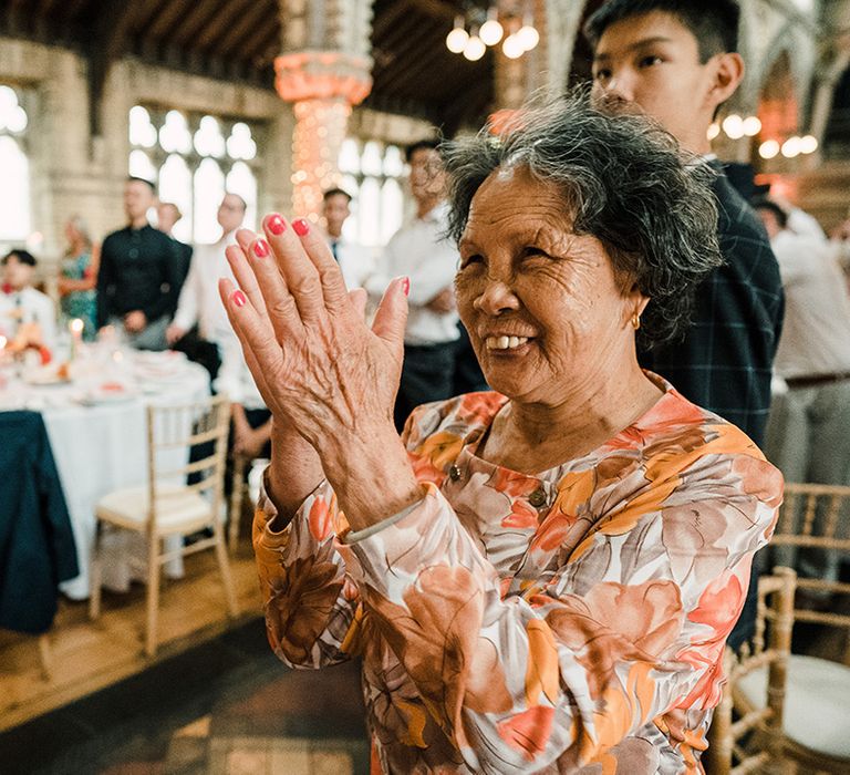 Wedding guest in colourful outfit claps during wedding reception 