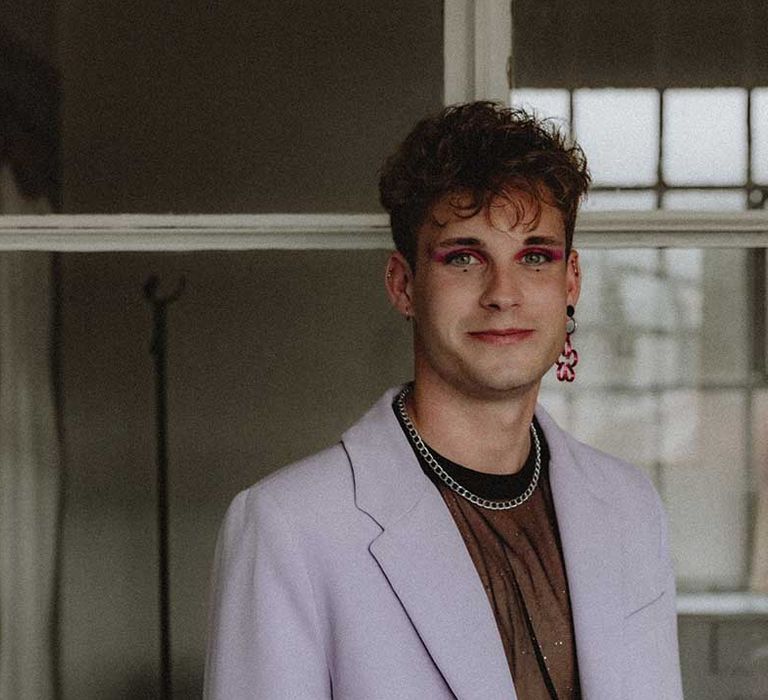 Wedding guest wears pastel purple suit complete with pink eyeshadow and floral earring