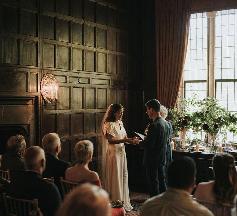 Bride puts on the groom's wedding ring as they participate in humanist and bespoke wedding ceremony at Askham Hall 