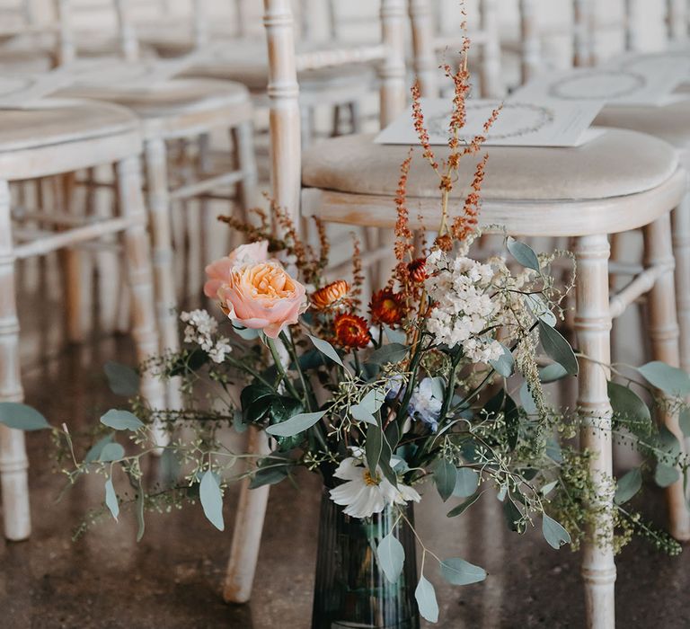 Seasonal florals within glass vase lining aisle at Trinity Buoy Wharf 