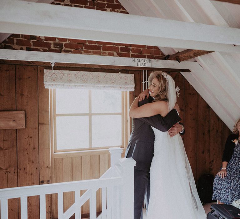 The bride and father of the bride share an embrace was he sees her in her wedding dress for the first time 