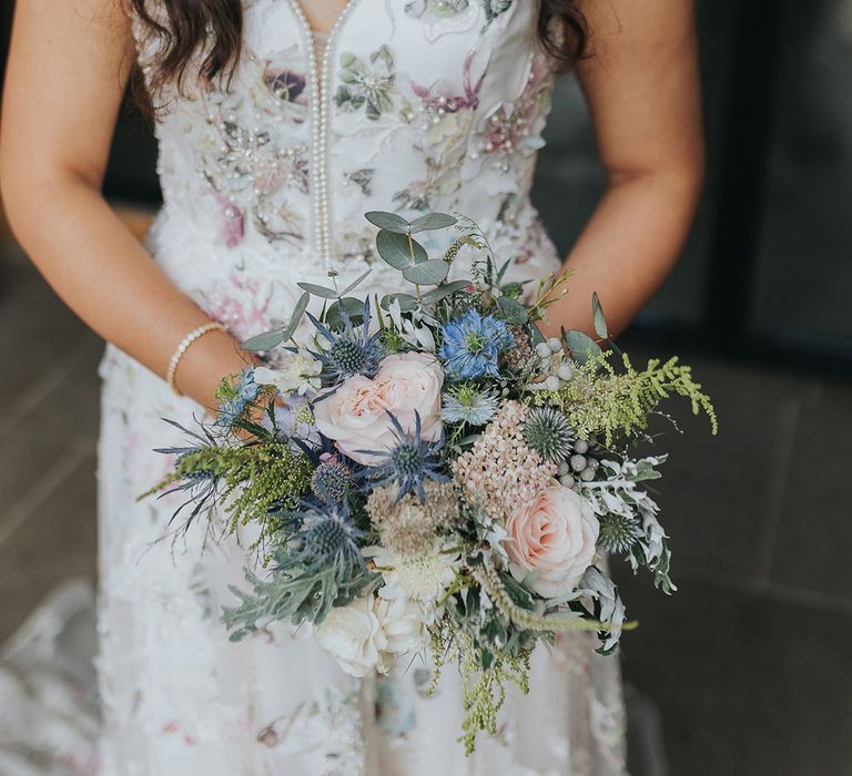 Floral wedding dress and seasonal wedding bouquet with pink roses and thistles 