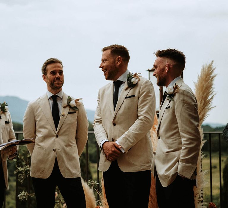 Groom and groomsmen in linen suits with white rose boutonnières at destination wedding in Tuscany