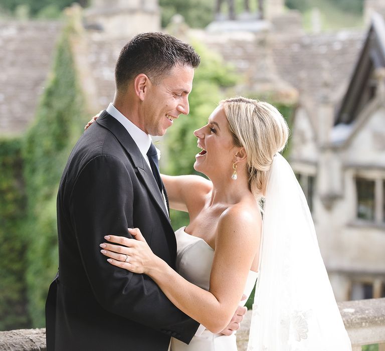 The bride and groom smile brightly together for their couple portraits at The Manor House, Castle Combe 