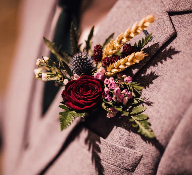 Rustic Cripps Barn wedding with the groom wearing a red rose, thistle and dried grass buttonhole 