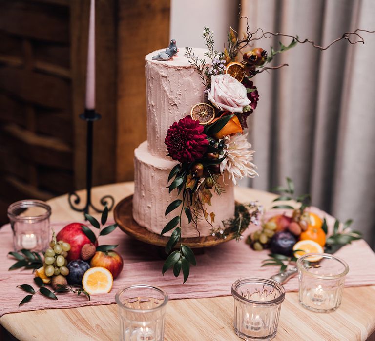 Two tier rustic pink iced wedding cake with mini fondant pigeon cake toppers with amazing wedding flower cake decoration with dried fruit