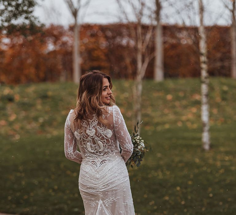 Bride in a long sleeve wedding dress with train and intricately detailed sequin back for winter wedding 