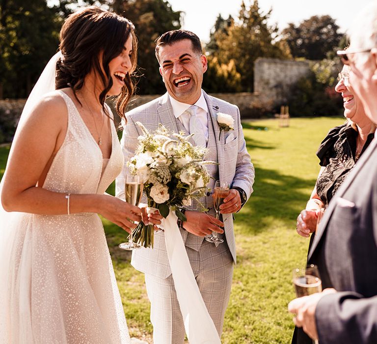 Bride in a sparkly wedding dress laughing during the drinks reception 