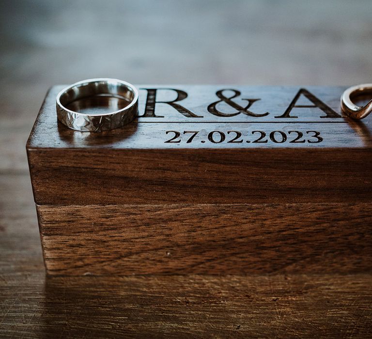 Personalised wooden wedding ring box with the couple's initials on with unique gold wedding bands 