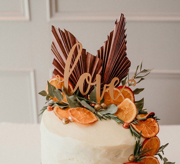 Single tier white iced wedding cake with dried fruit orange slices and wooden cake topper 