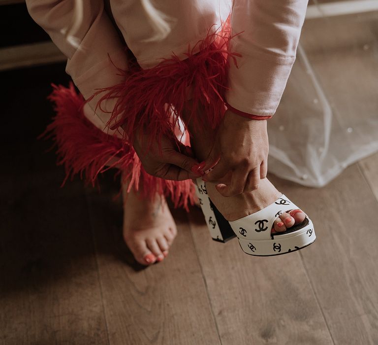 Black and white Chanel platform wedding shoes worn by the bride in pink pyjamas with dark pink feather cuff 