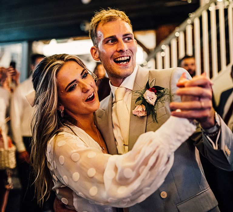 first dance at East Quay Whitstable wedding venue with groom in a grey suit and bride in a long sleeve bridal jumpsuit 