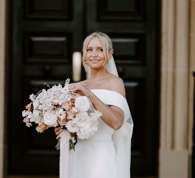 Pink roses with white and peach florals in pastel bouquet in bow wedding dress and veil 