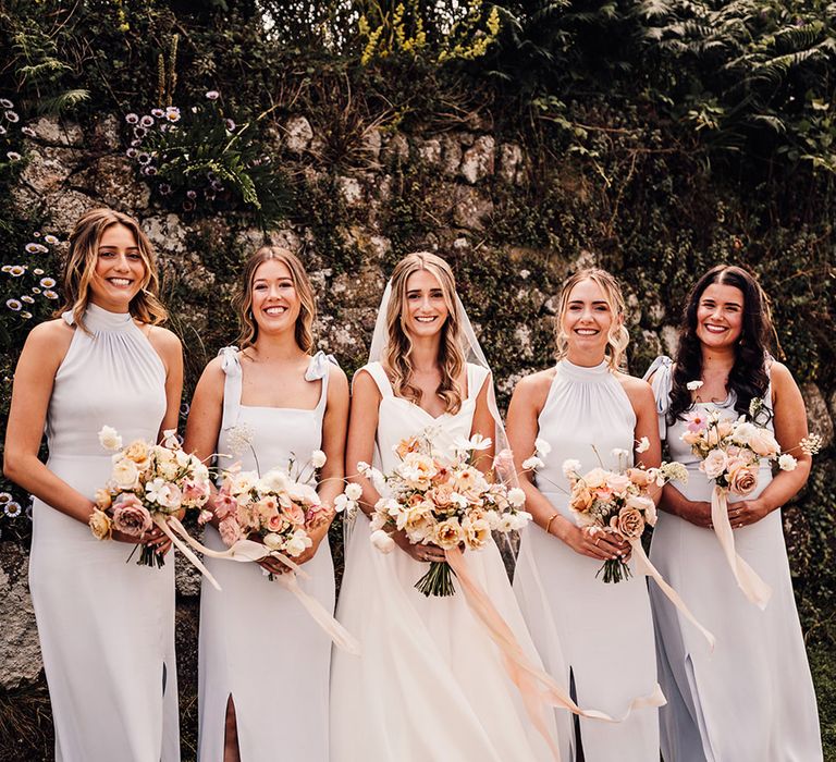 bridal party wearing pale blue bridesmaid dresses and holding blush wedding bouquets 