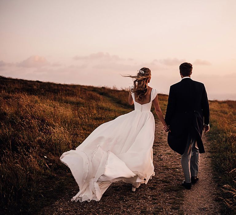 bride in a Suzanne Neville princess wedding dress billowing in the wind at Sennen Cove wedding 