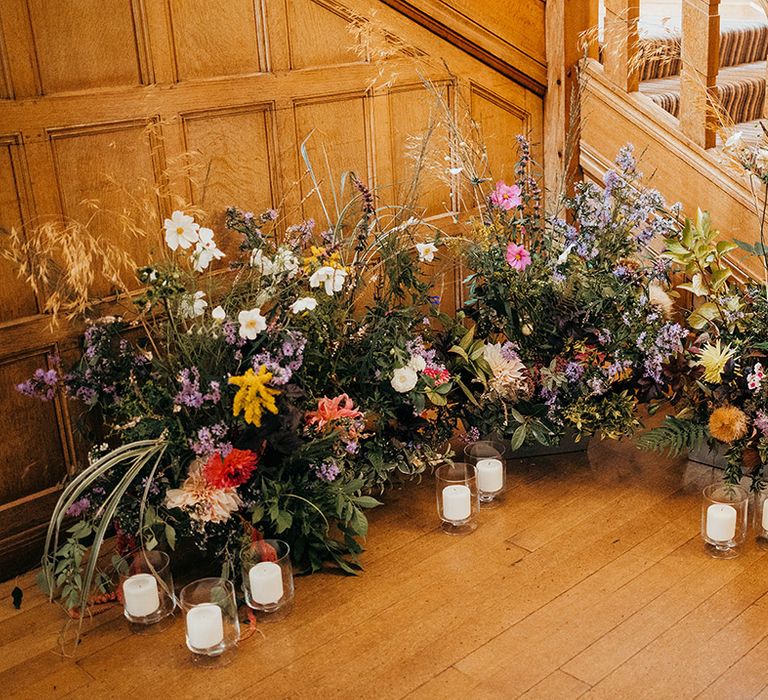 Colourful meadow wedding flowers decorating the bottom of the stairs 