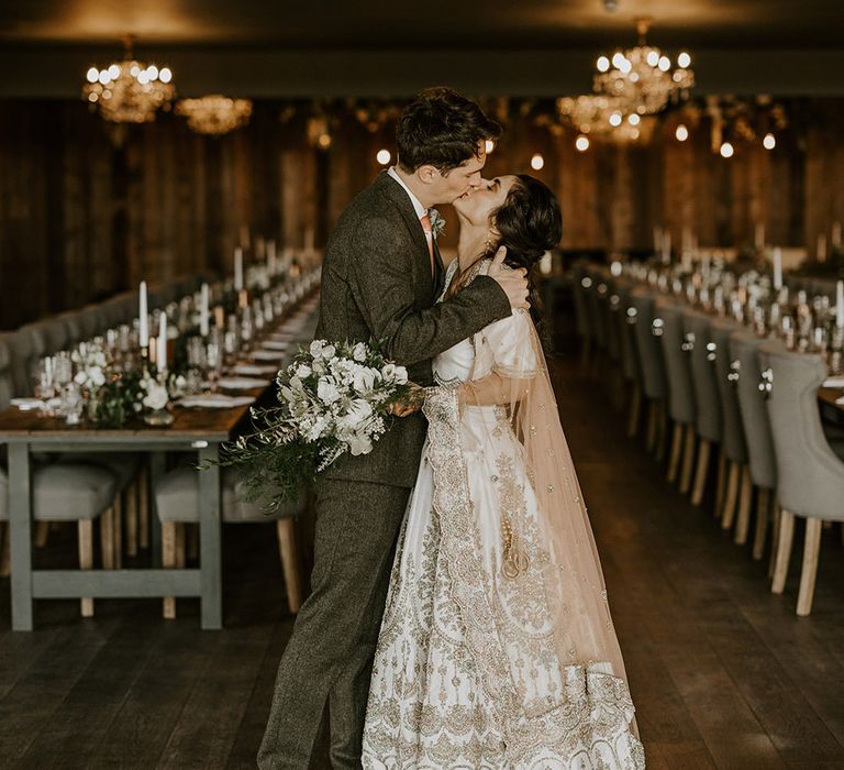 Wharfedale Grange wedding with the bride in a white and gold lehenga kissing groom 