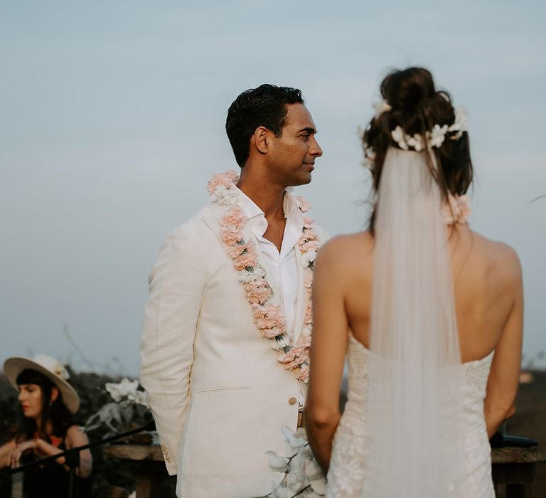 Indian groom in cream groom suit with traditonal pink flower Varmala