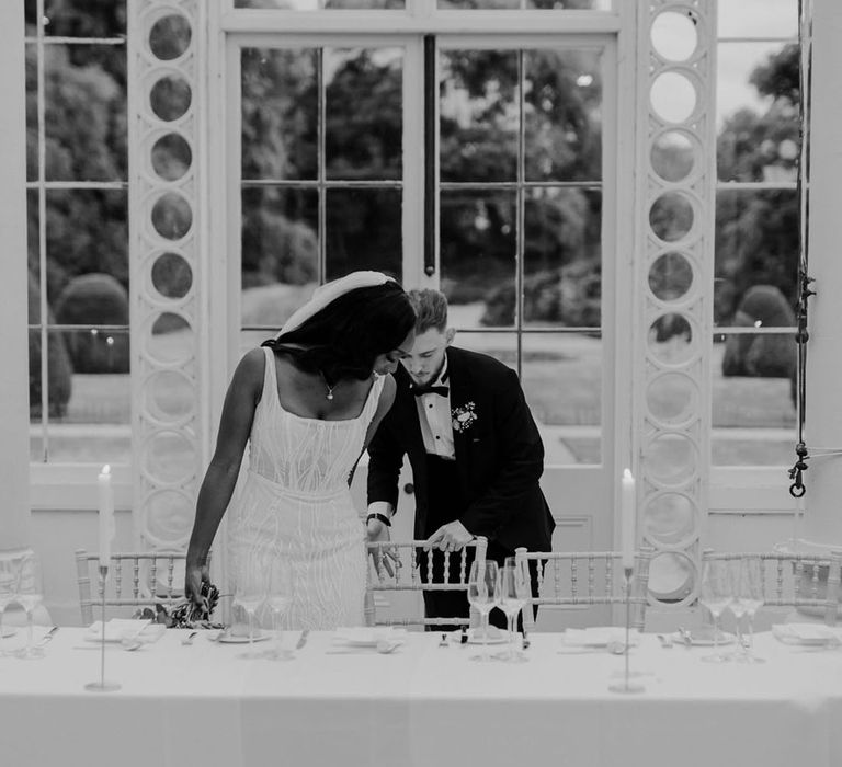 The bride and groom sit down at the top table at their wedding reception at Syon Park