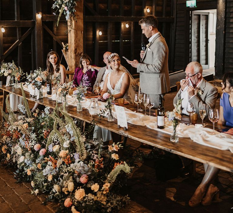 Groom stands up at the wedding table and reads out his wedding speech at Elmley Nature Reserve rustic country house wedding venue 