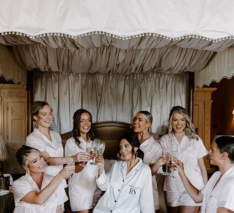 Bridal party in white satin pyjamas getting ready together on the morning of the wedding 