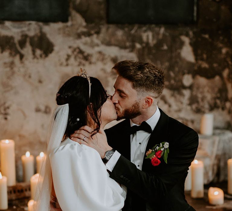 Groom in black tuxedo with bride wearing puff sleeve wedding dress and front slit with veil 