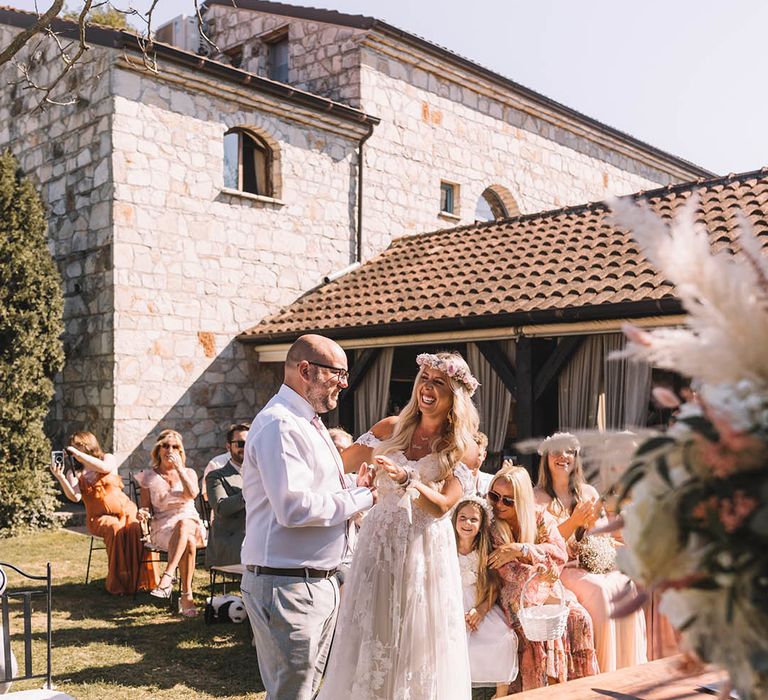 Groom in white shirt with pink tie with the bride in an off the shoulder wedding dress at their outdoor wedding ceremony