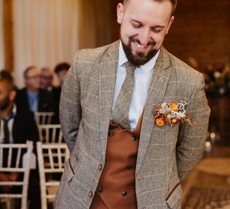 Groom wearing three piece brown checkered suit for the autumnal boho wedding 