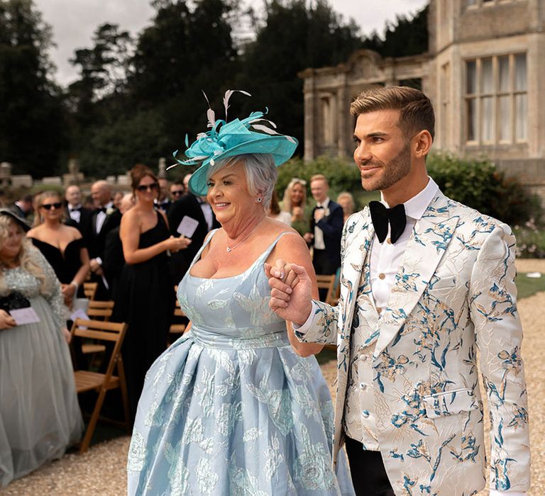 Groom in blue patterned suit jacket with the mother of the groom in a blue dress with fascinator 