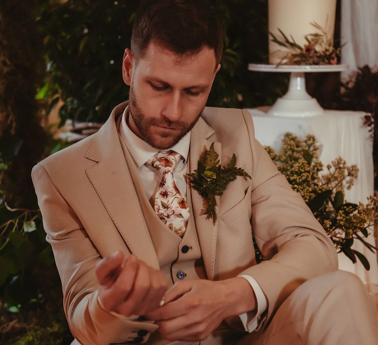 Groom in light grey three piece wedding suit with floral tie and foliage buttonhole 