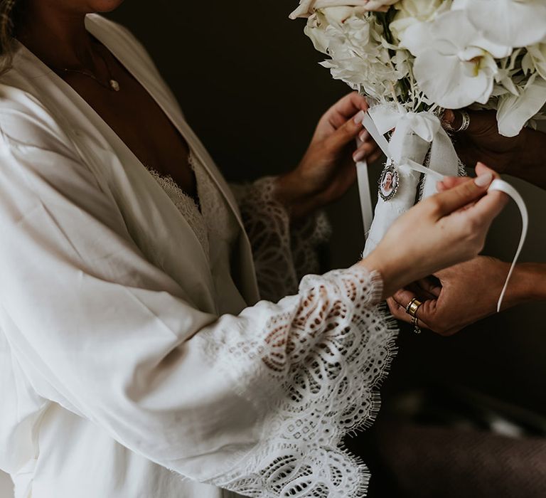 Bride ties the bouquet charm onto the wedding bouquet 