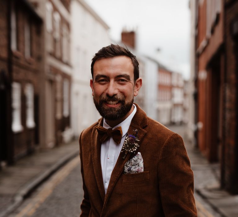 Stylish groom in cord jacket and bow tie at micro wedding 