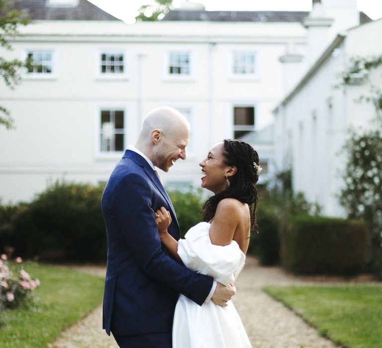 Groom in navy wool suit embracing his bride at Morden Hall wedding 