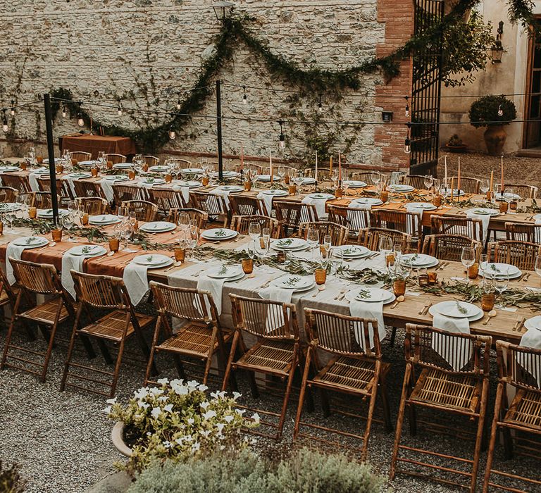 Wooden banquet tables decorated with foliage and earthy toned linens and candles 