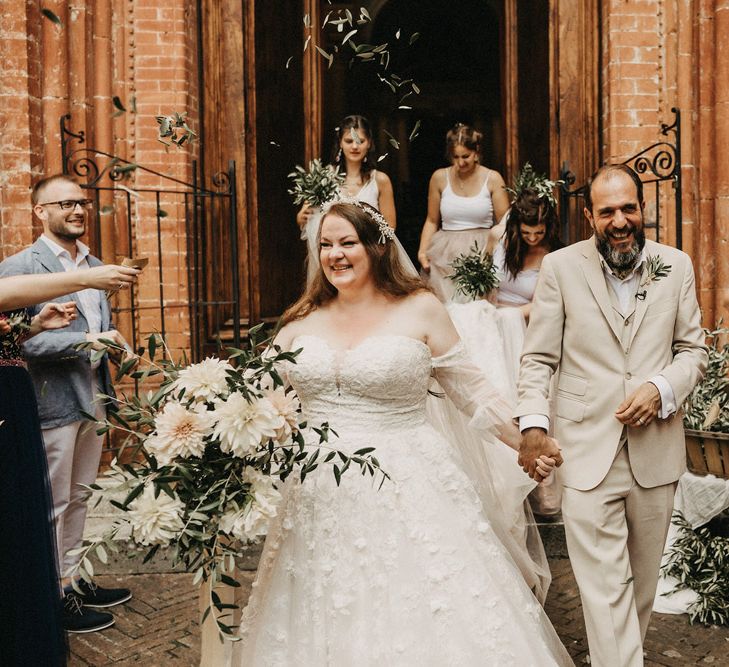 couple holding hands with olive bouquets thrown over them