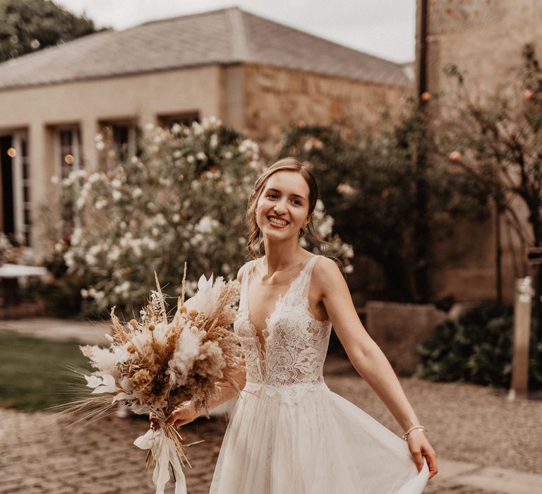 Smiling bride in Watters wedding dress with dried flower wedding bouquet 