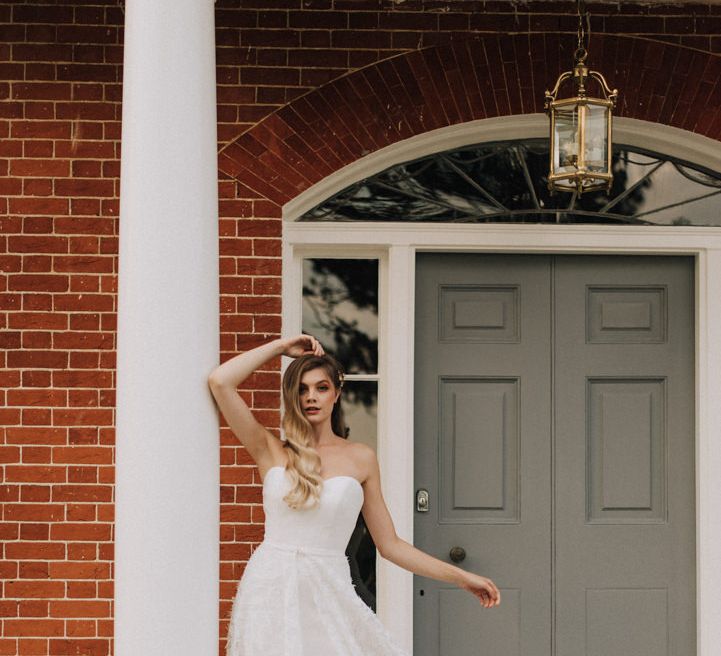 bride wears strapless feathered skirt wedding dress on the steps of Reymerston Hall